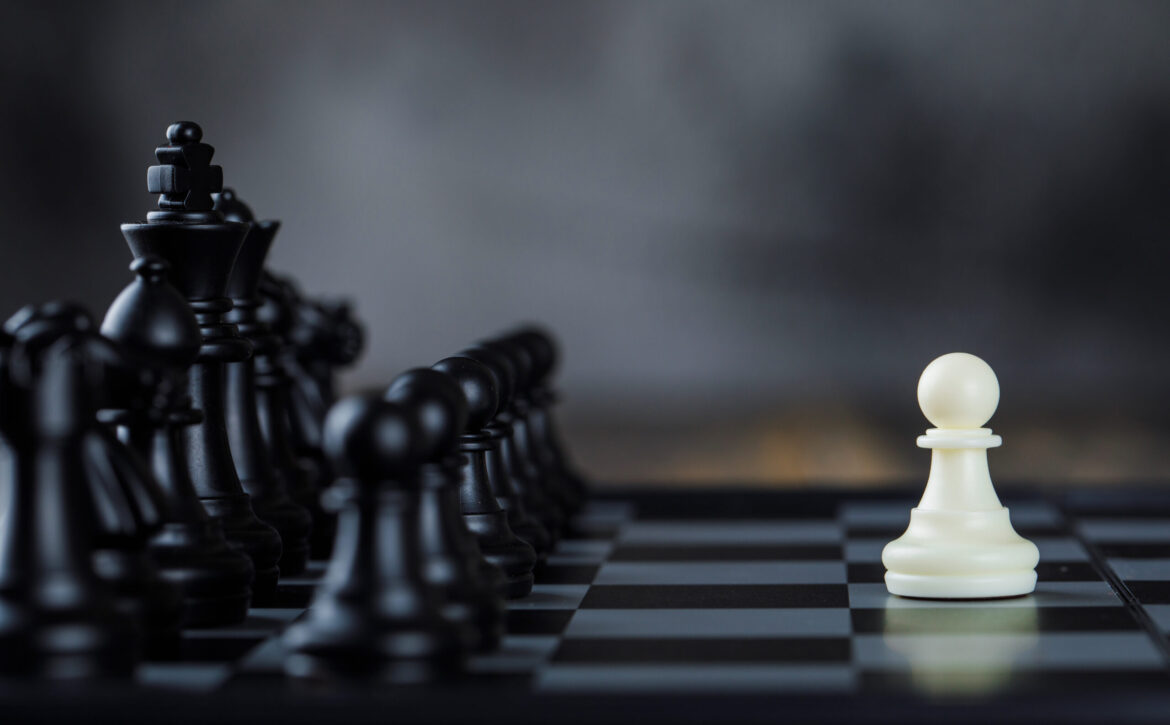 Business strategy concept with figures on chessboard on foggy and wooden background side view.