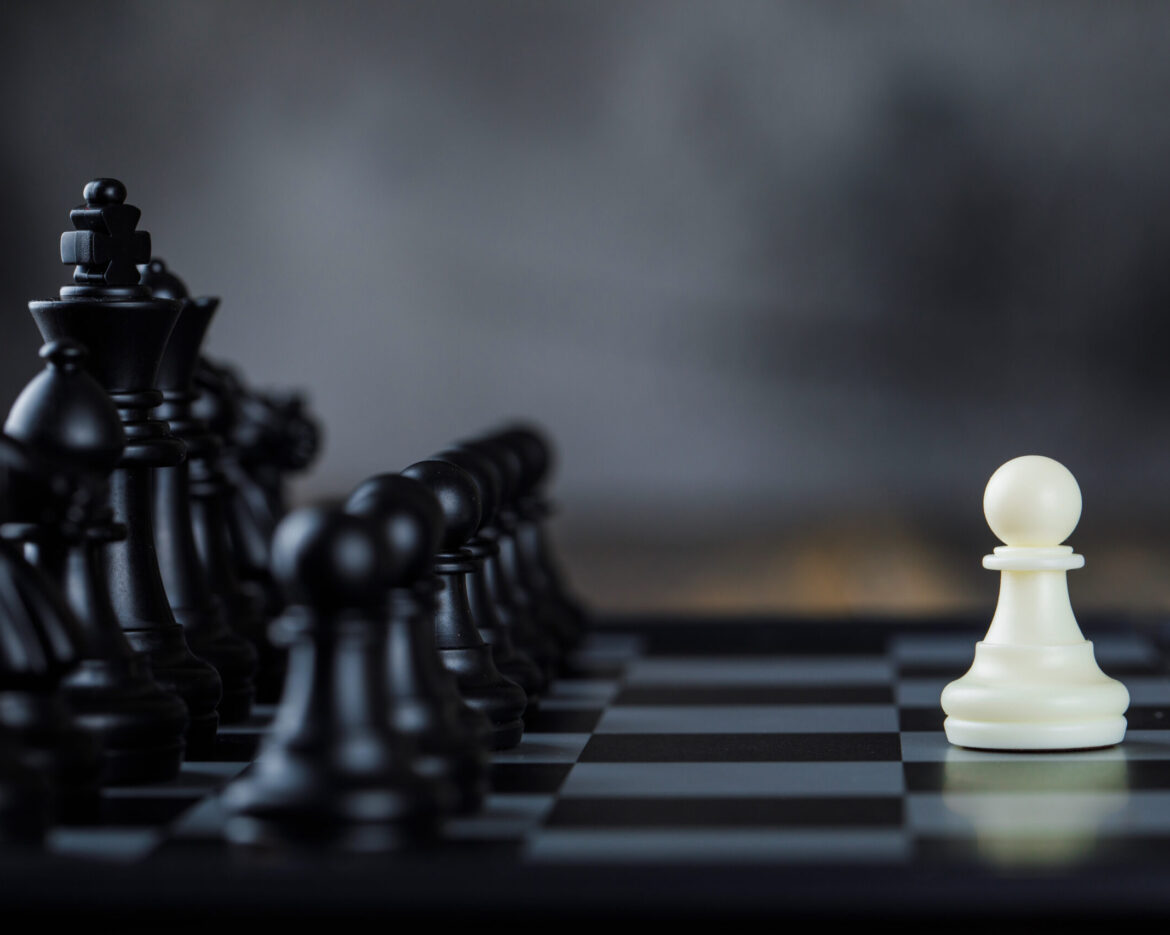 Business strategy concept with figures on chessboard on foggy and wooden background side view.